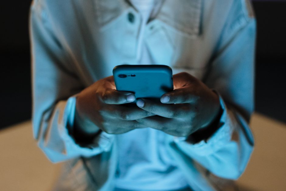 Hands holding a smartphone in dim teal light, representing searching Instagram for an account that appears in a data export but will not open