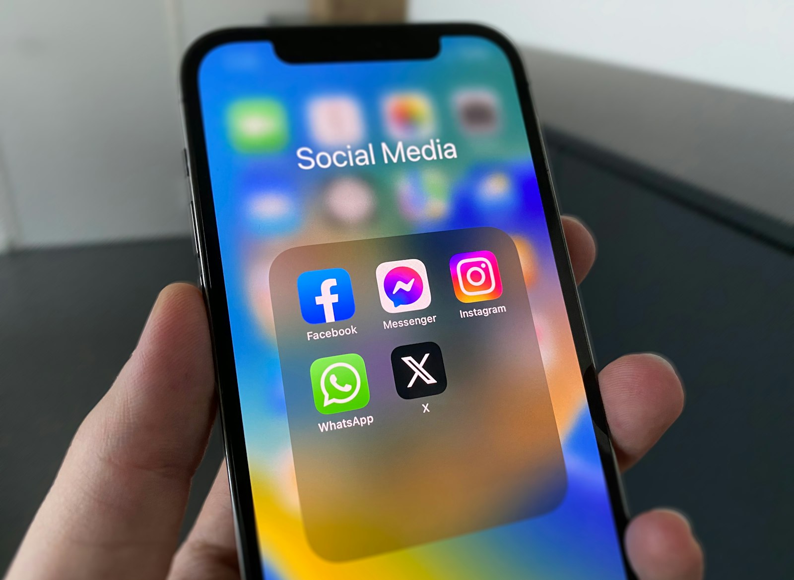 A hand holding a phone showing a folder of social media apps including Instagram, representing checking why someone disappeared from a followers list