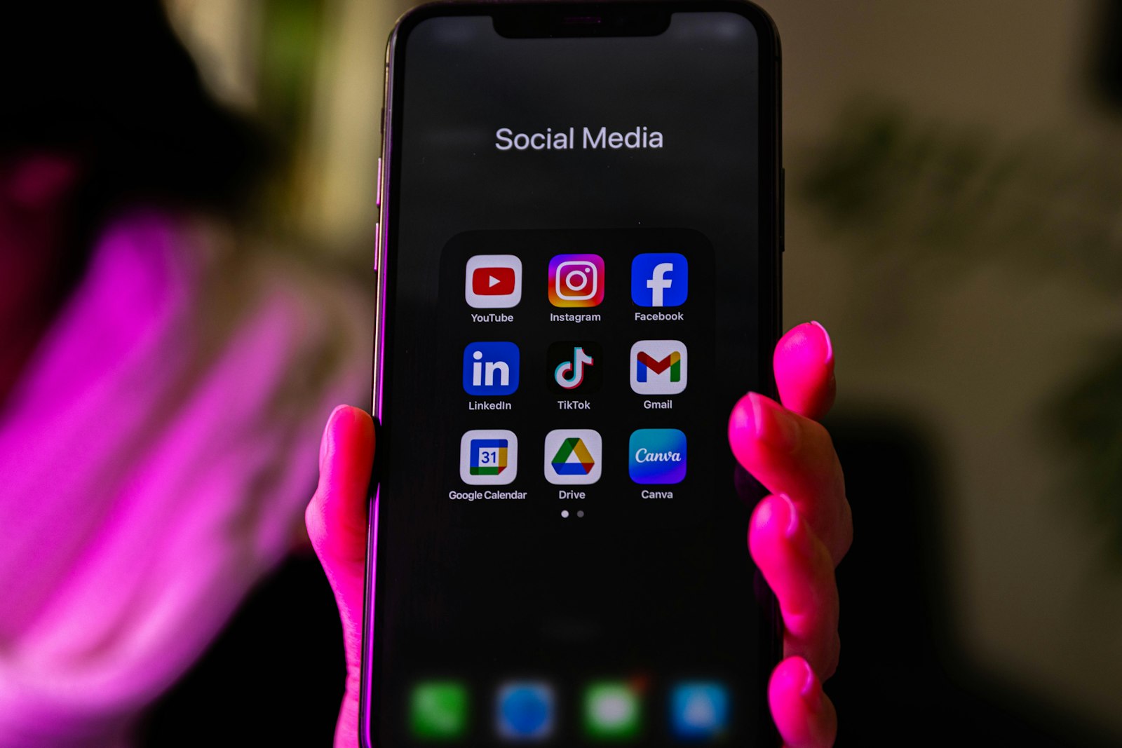 A hand holding a smartphone showing social media apps, representing spotting the follow and unfollow tactic on Instagram
