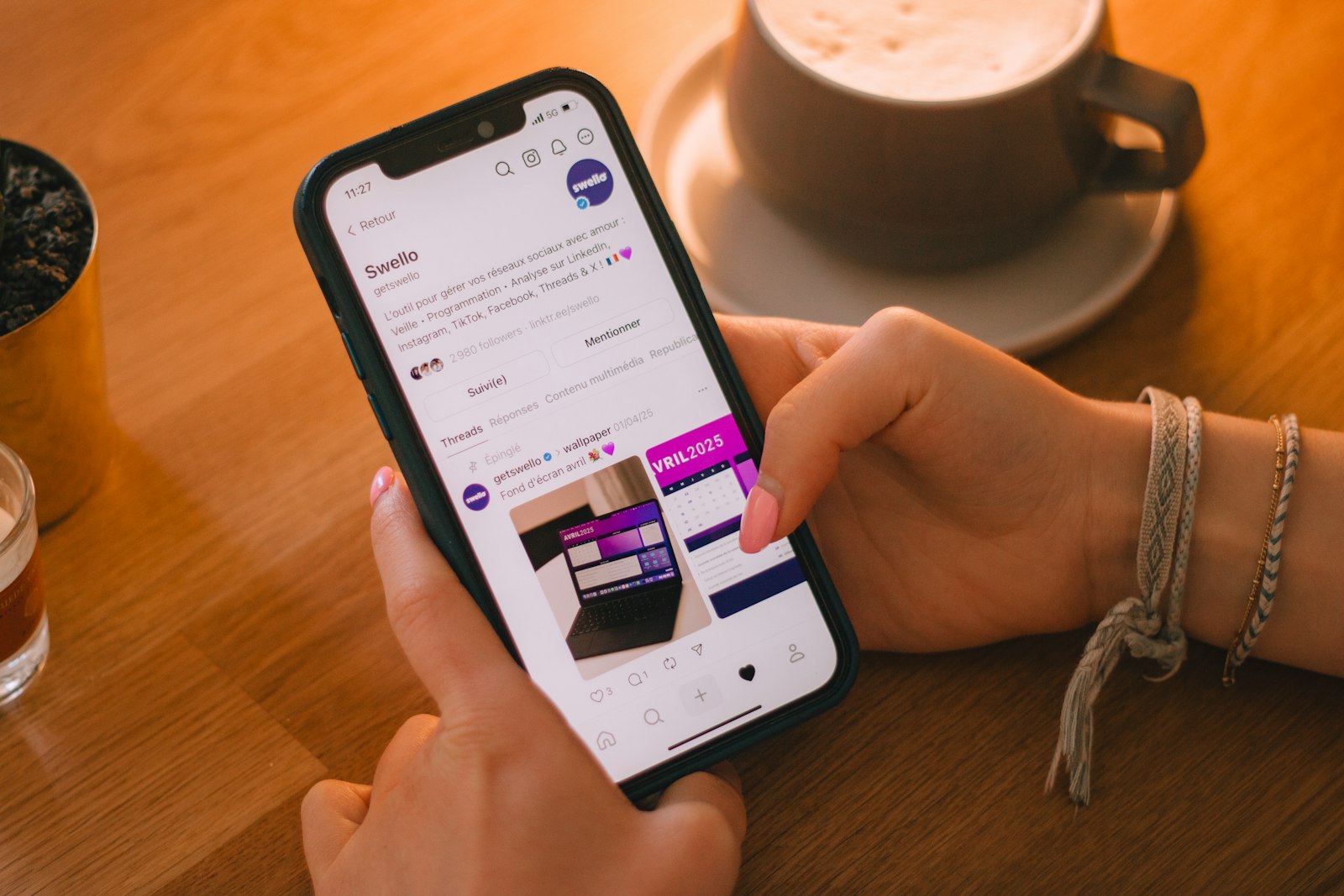A hand scrolling through a phone showing social media apps, representing unfollowing accounts on Instagram
