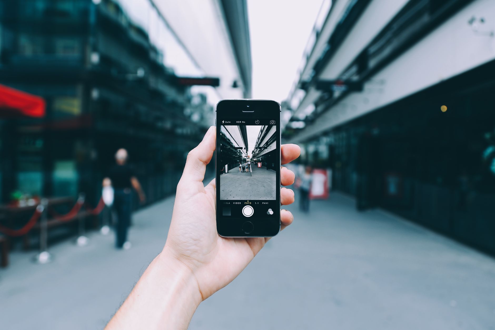 A close-up of a hand holding a smartphone taking a photo, representing sharing an Instagram Instant with mutual followers