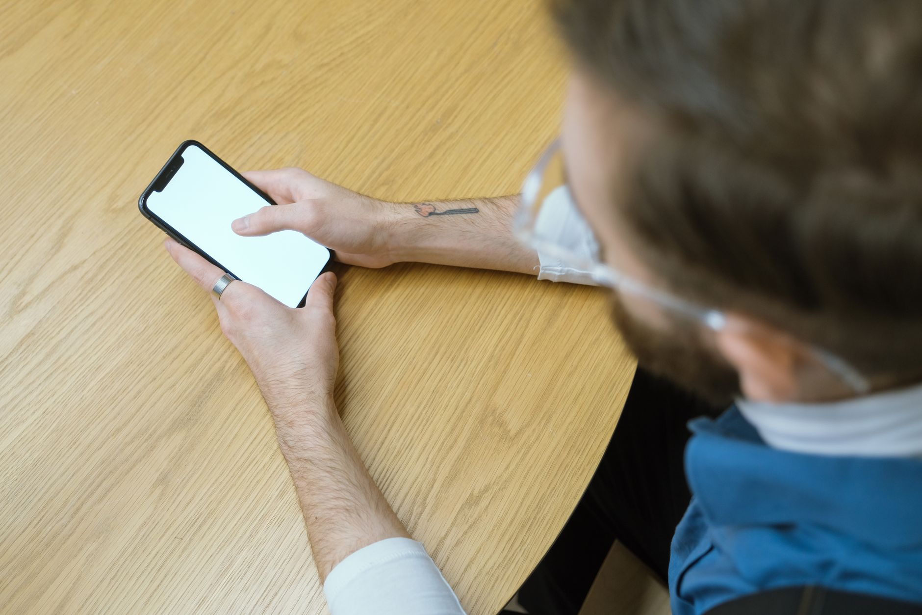 An overhead view of a person quietly holding a smartphone at a table, representing checking privately whether an ex unfollowed you on Instagram