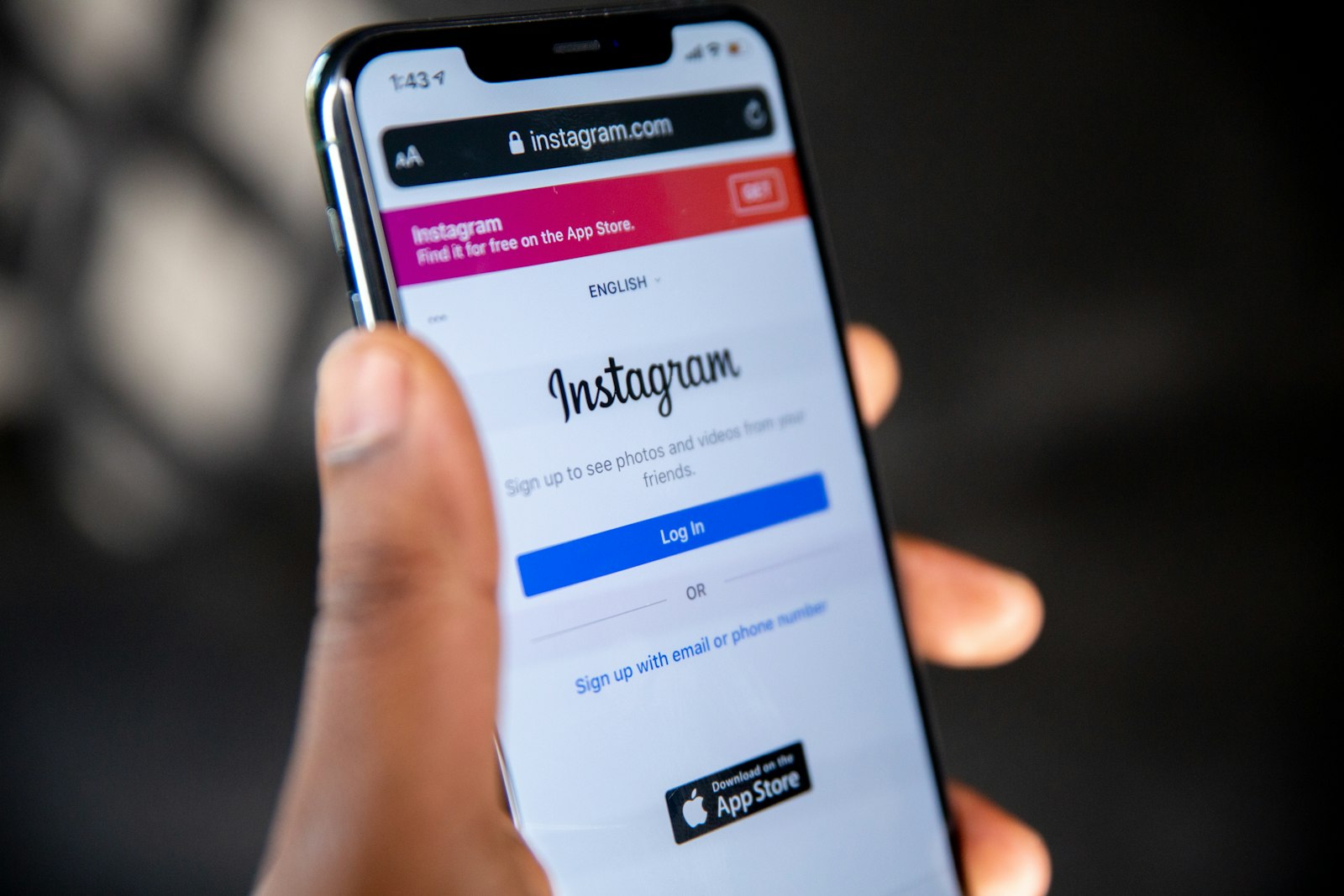 A hand holding a phone open to the Instagram login screen