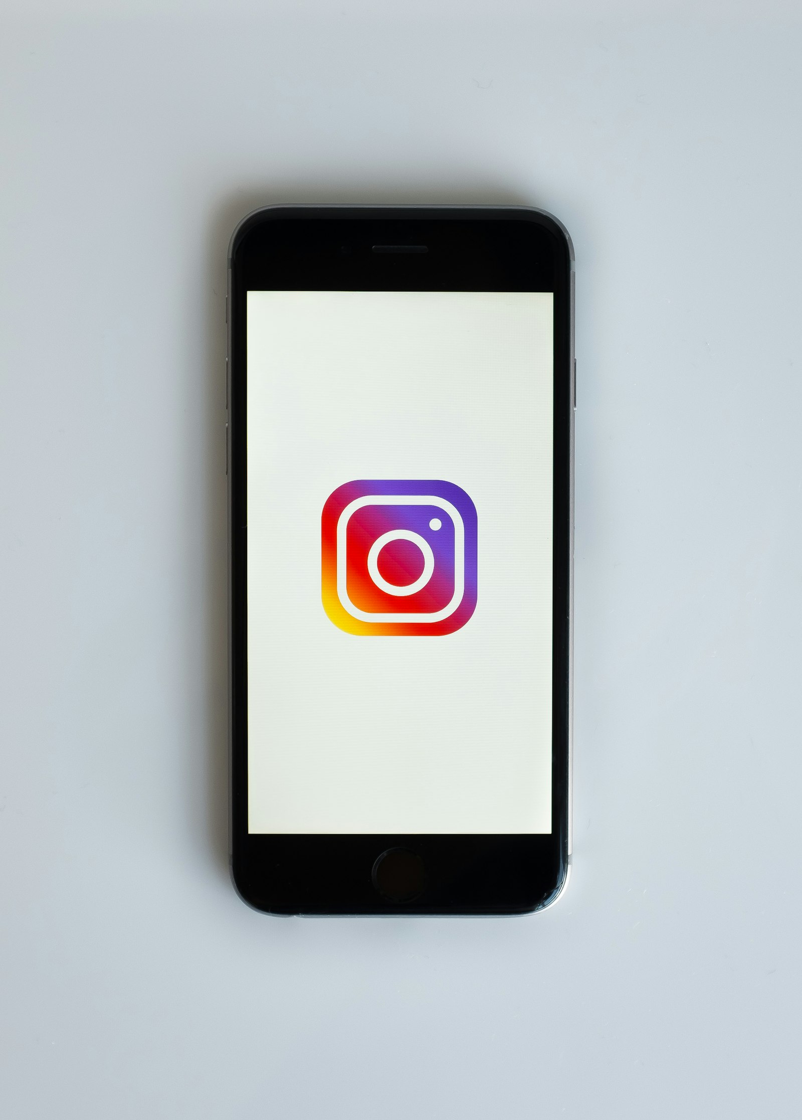 A smartphone displaying the Instagram logo on a plain background, representing unfollowing accounts on Instagram