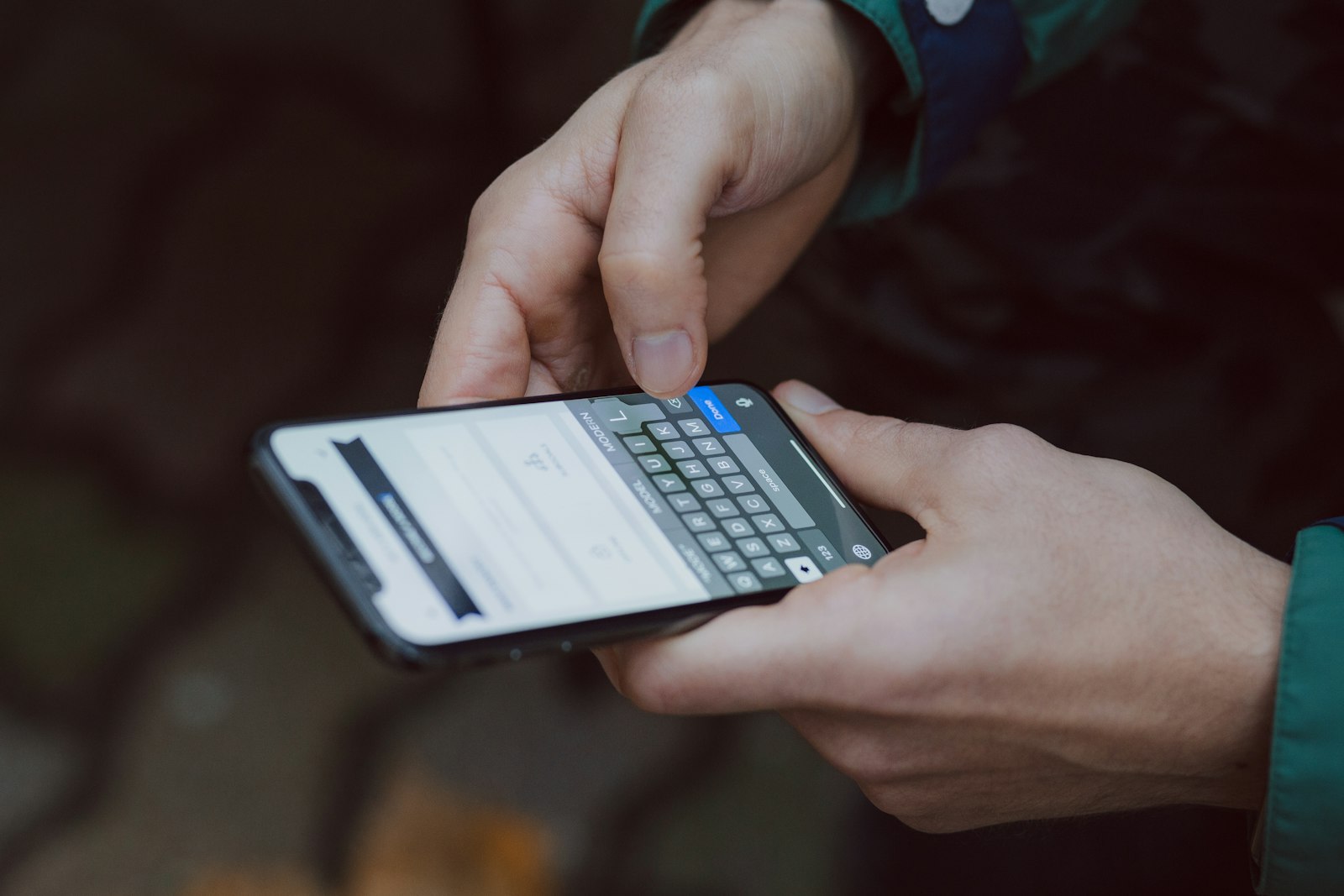 Two hands typing a message on a phone keyboard