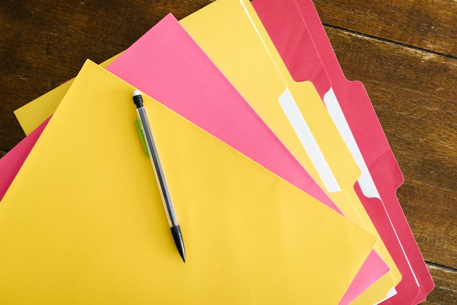 Colorful folders and a pen arranged on a wooden table, representing the files inside a Threads data export ZIP