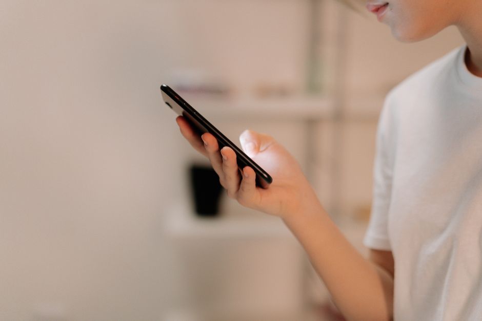 A person using a smartphone indoors, representing checking who does not follow you back on Threads