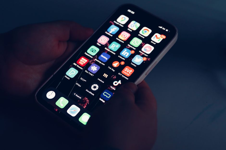 Hands holding a smartphone in dim lighting, representing checking Threads followers for free