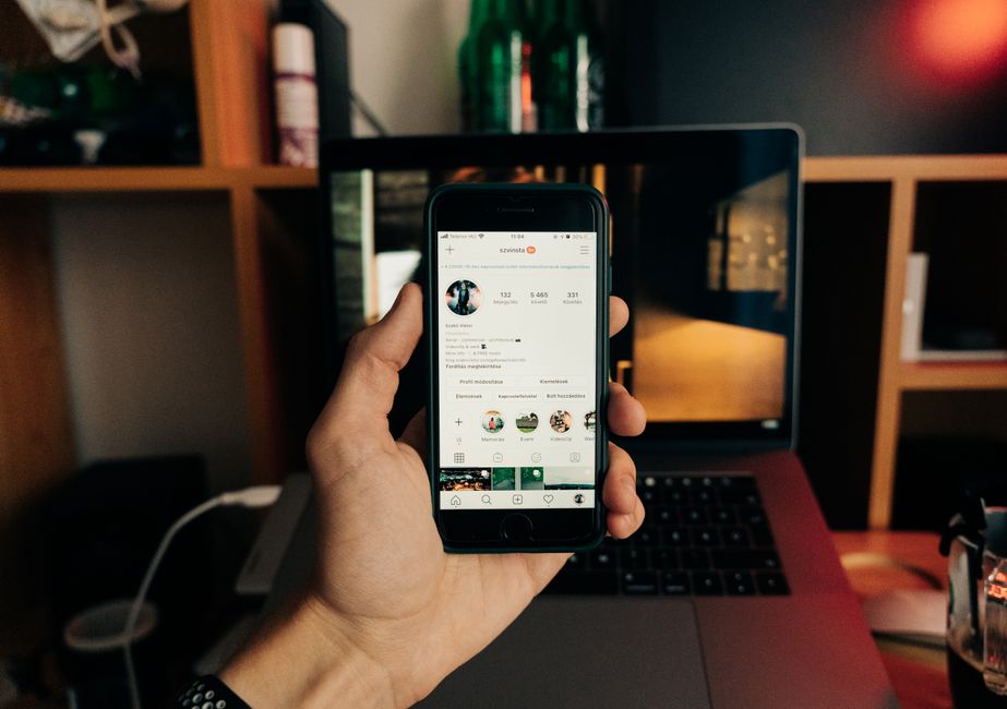 A hand holding a smartphone with Instagram open, representing checking who unfollowed you from a phone