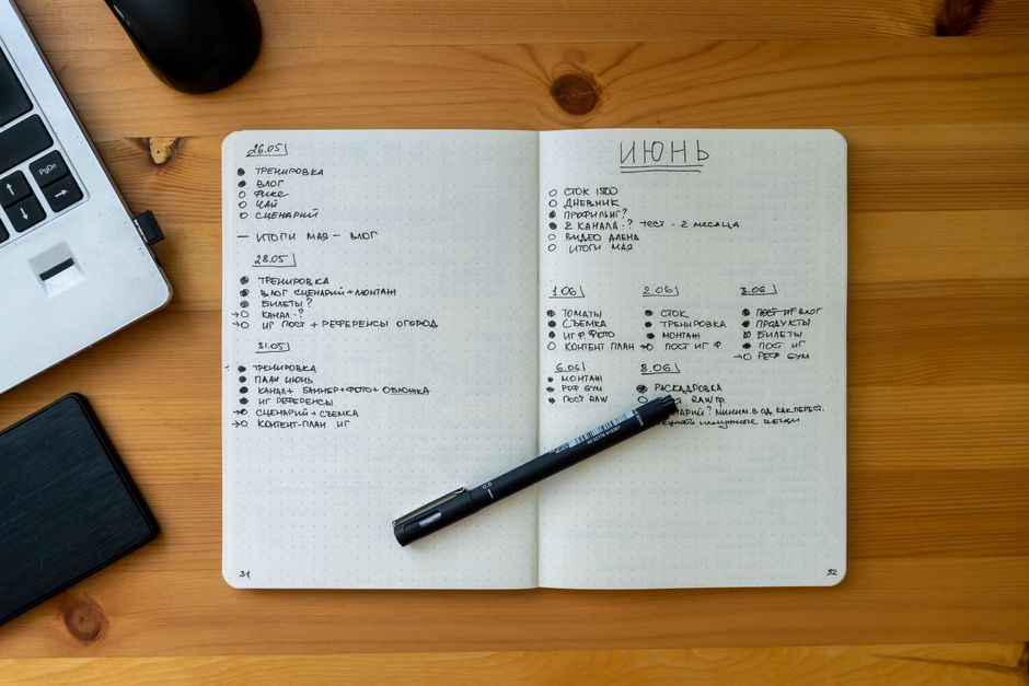 An open notebook with handwritten notes on a wooden desk beside a laptop, representing comparing two follower lists